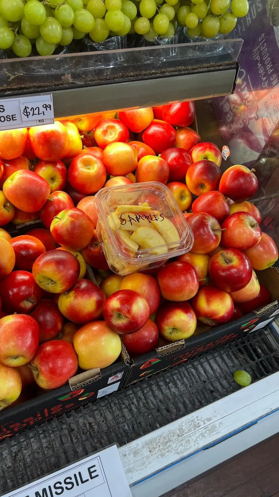 Green grapes and red apples stacked on the display with tasting samples