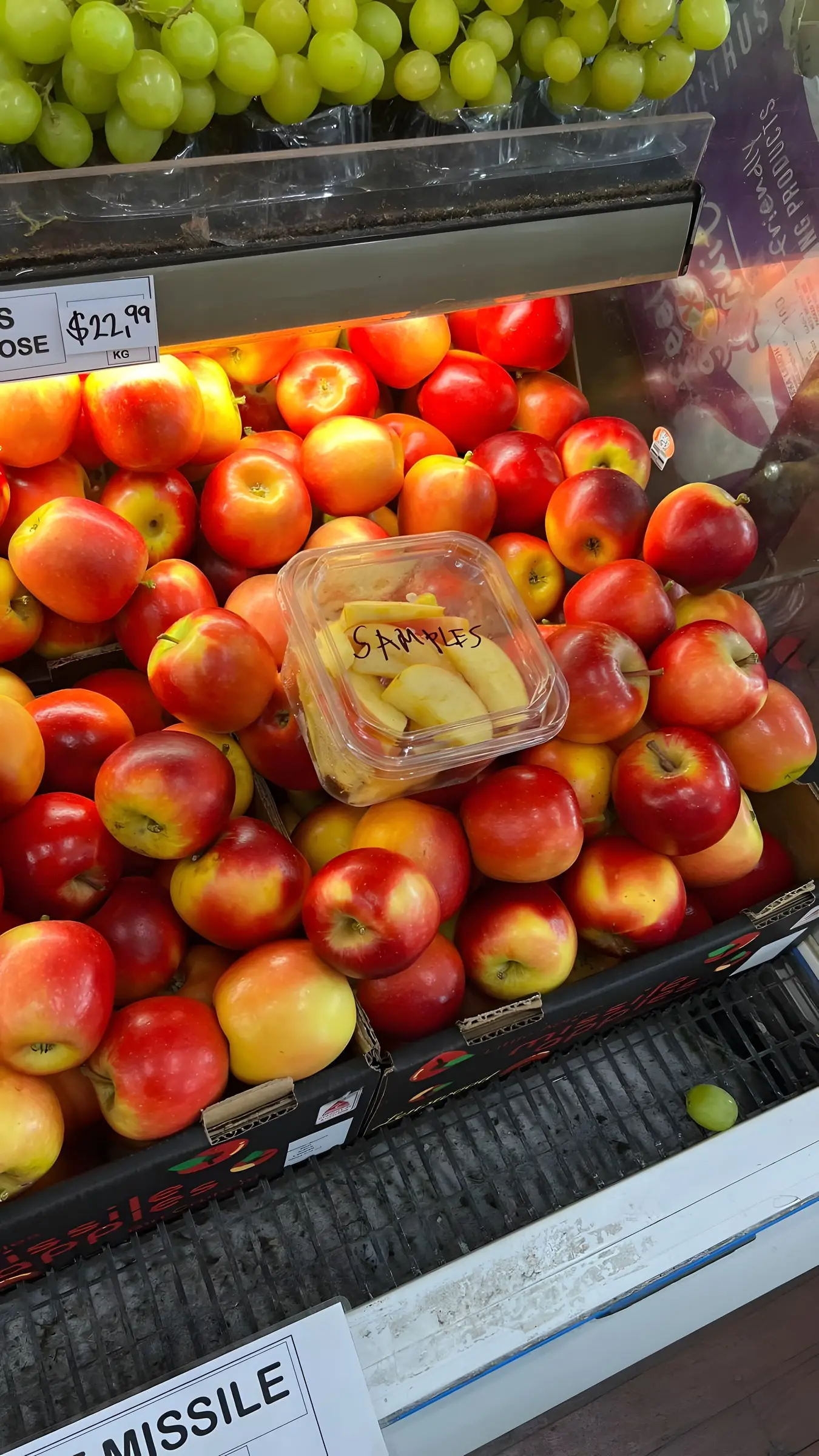 Fresh apples stacked on the produce display with a sample pack