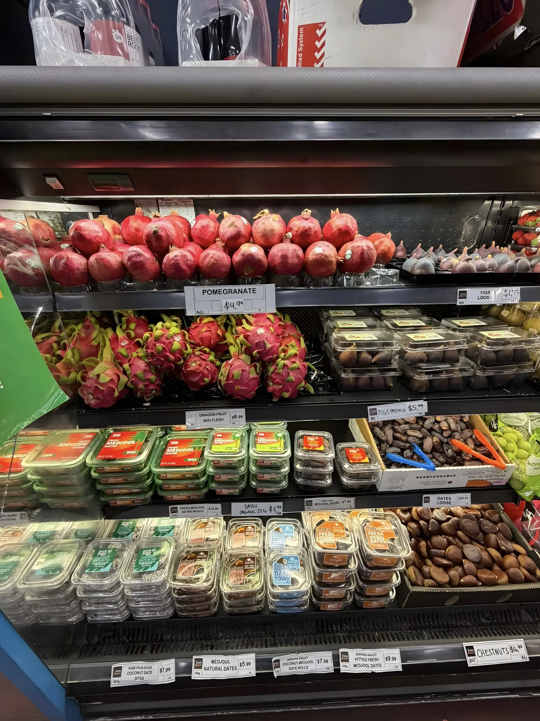 Pomegranates, dragon fruit, figs and dates displayed with handwritten price cards