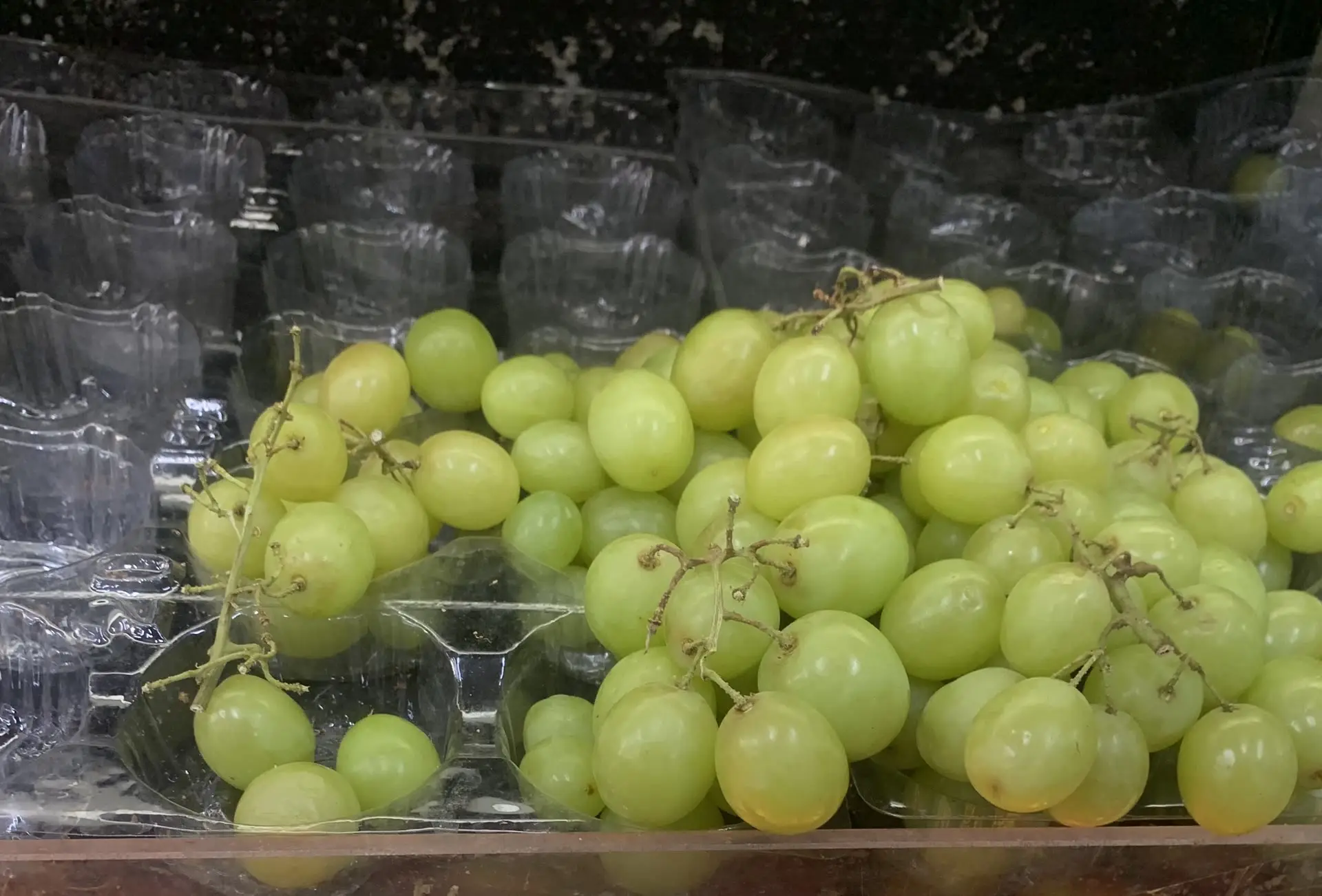 Loose green seedless grapes piled on the display bench