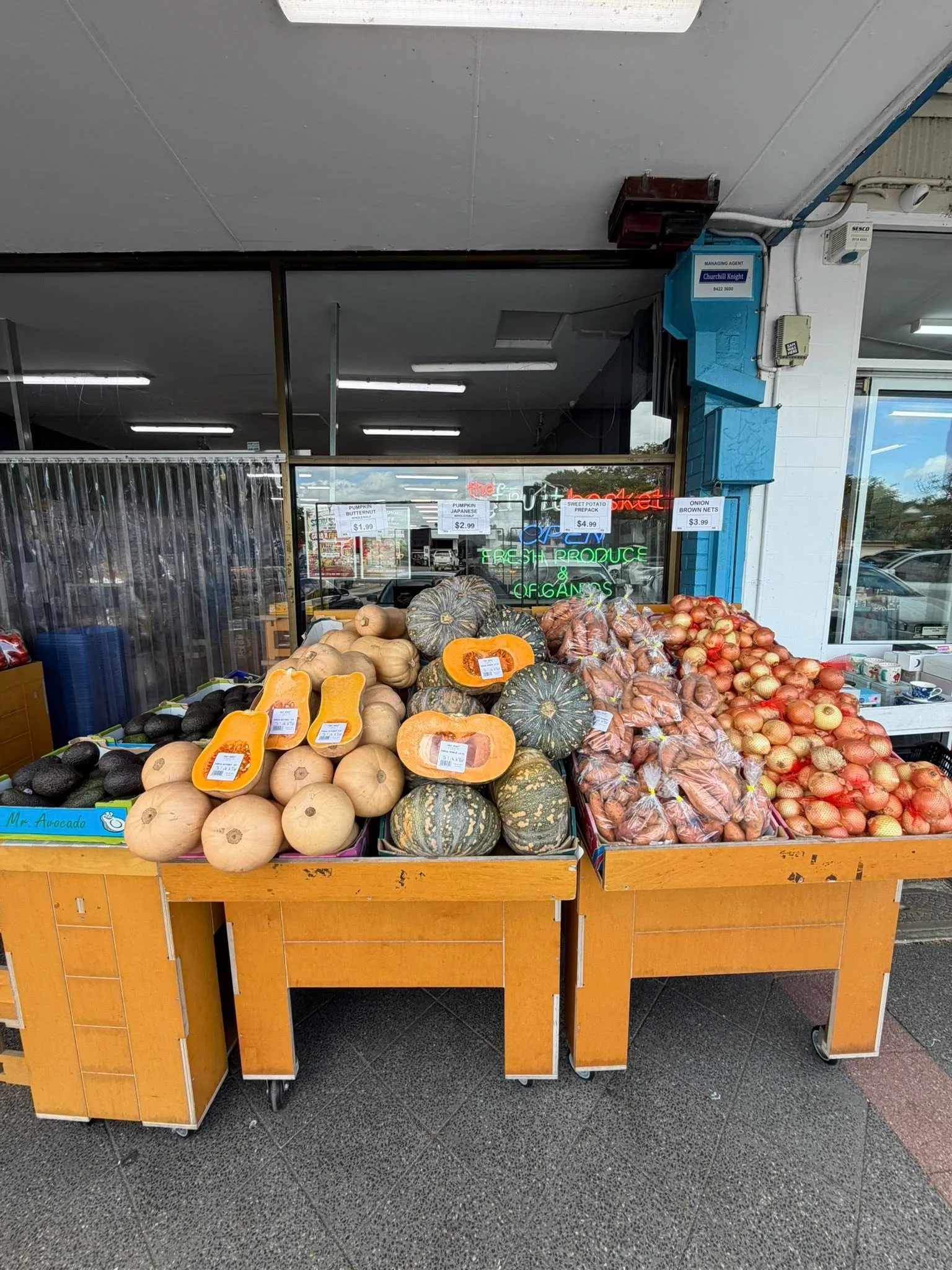 Wooden grocery displays at the shop entrance with seasonal produce and pantry items
