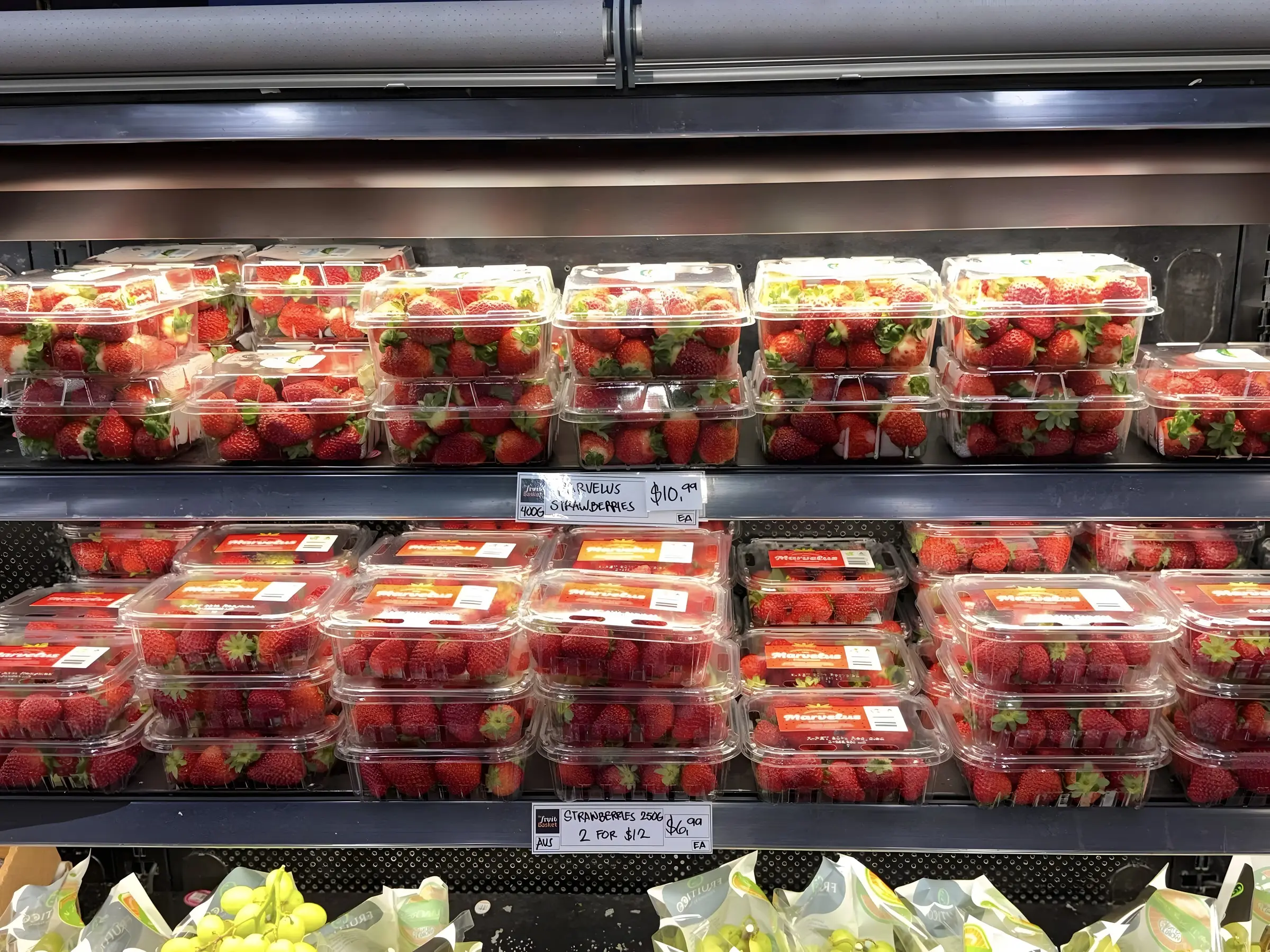 Trays of fresh strawberries in the refrigerated display case